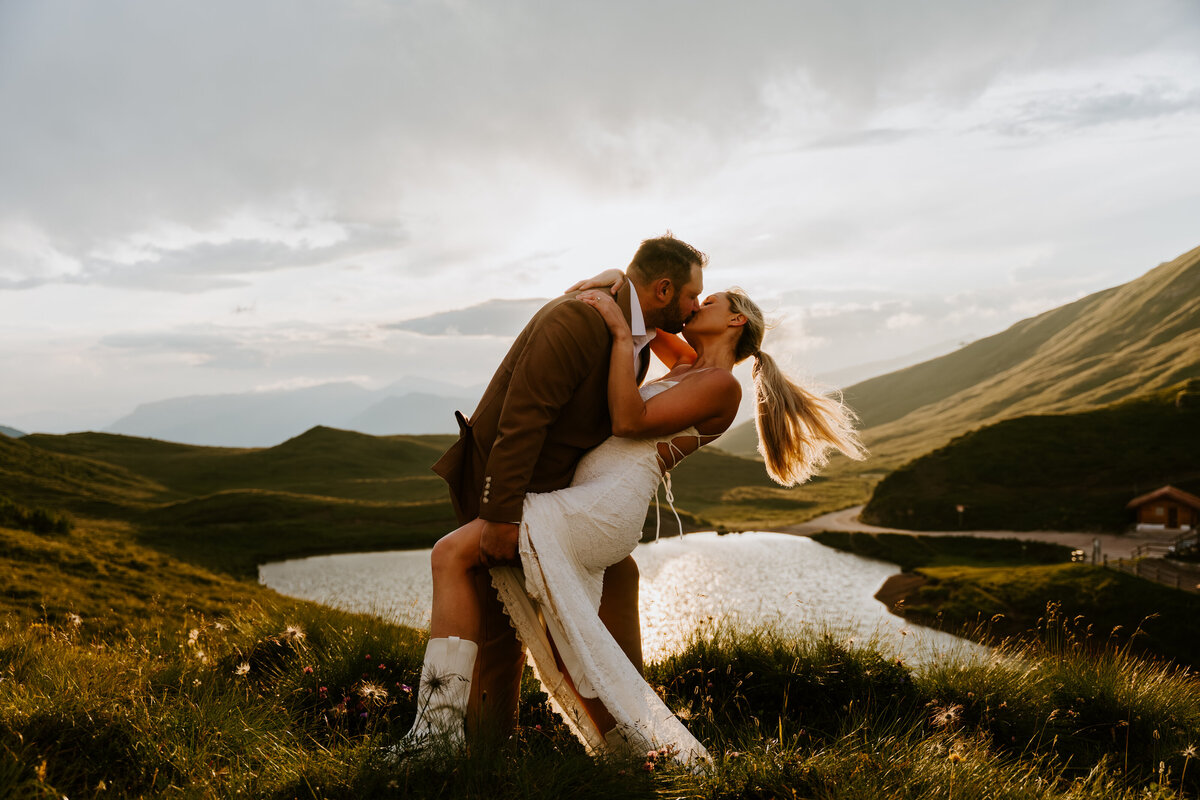 Couple kissing at sunset beside alpine lake in the Dolomites