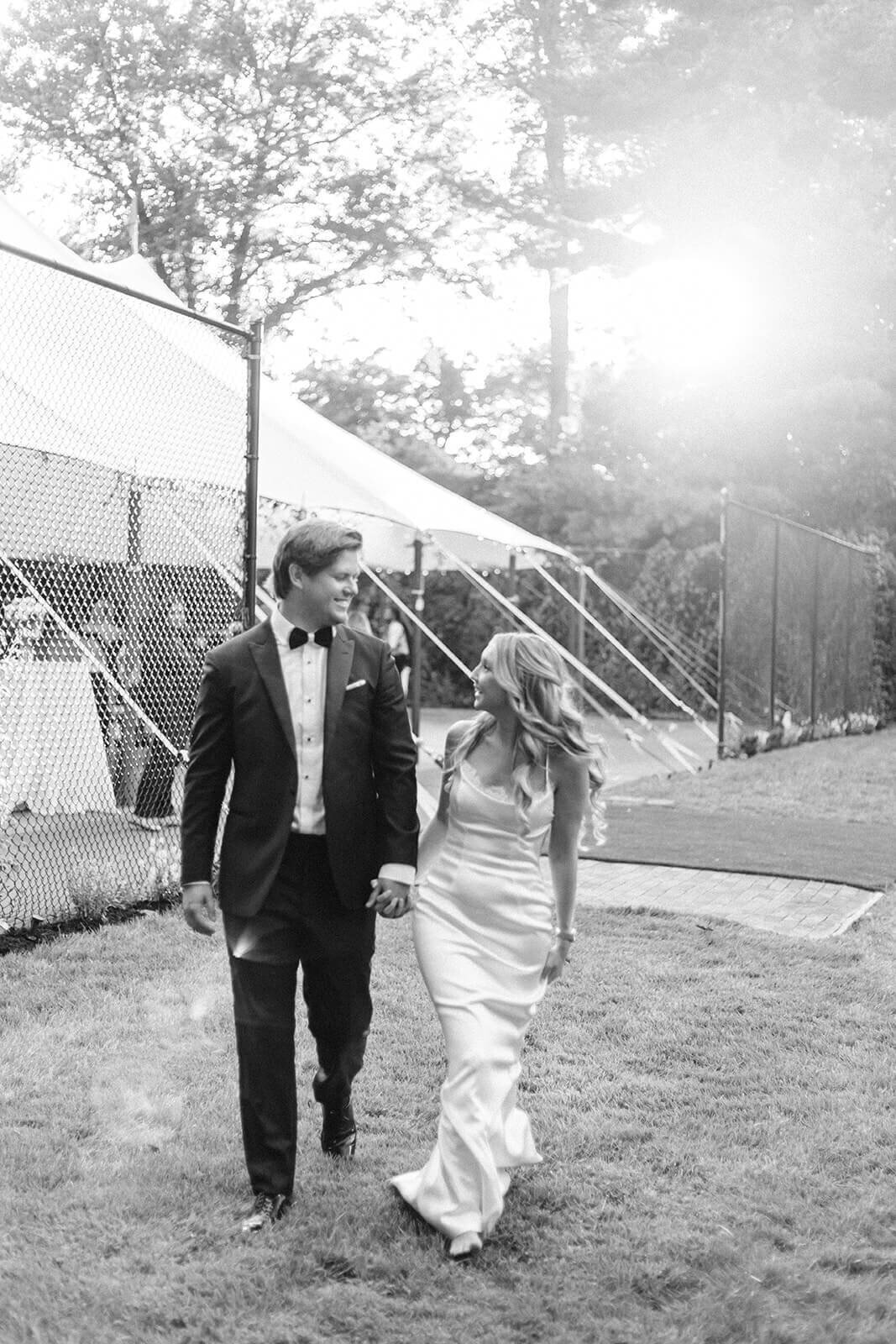 Bride and groom walking away from marquis at Long Island wedding reception