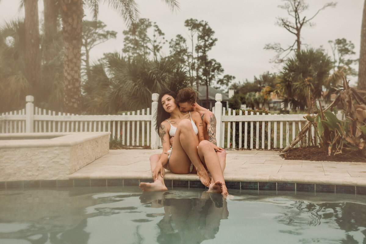 Young couple snuggles on edge of pool in their swimsuites in Panama City Beach Florida