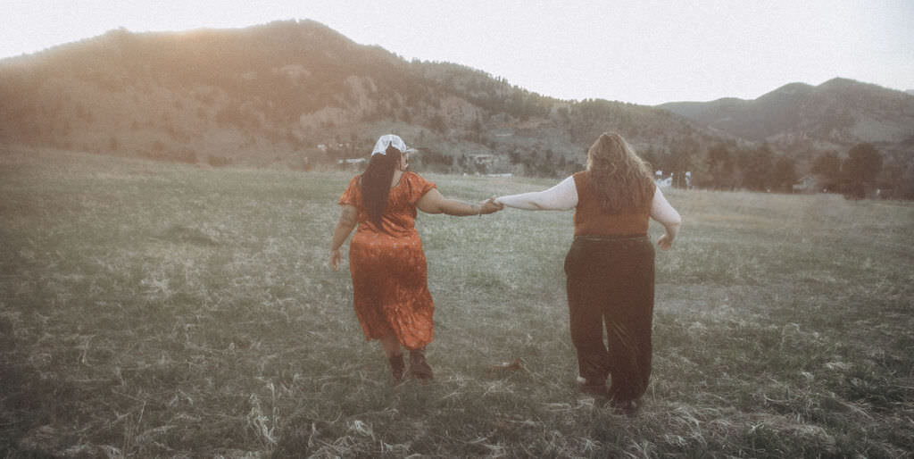 A couple reaching out towards each other in a field.