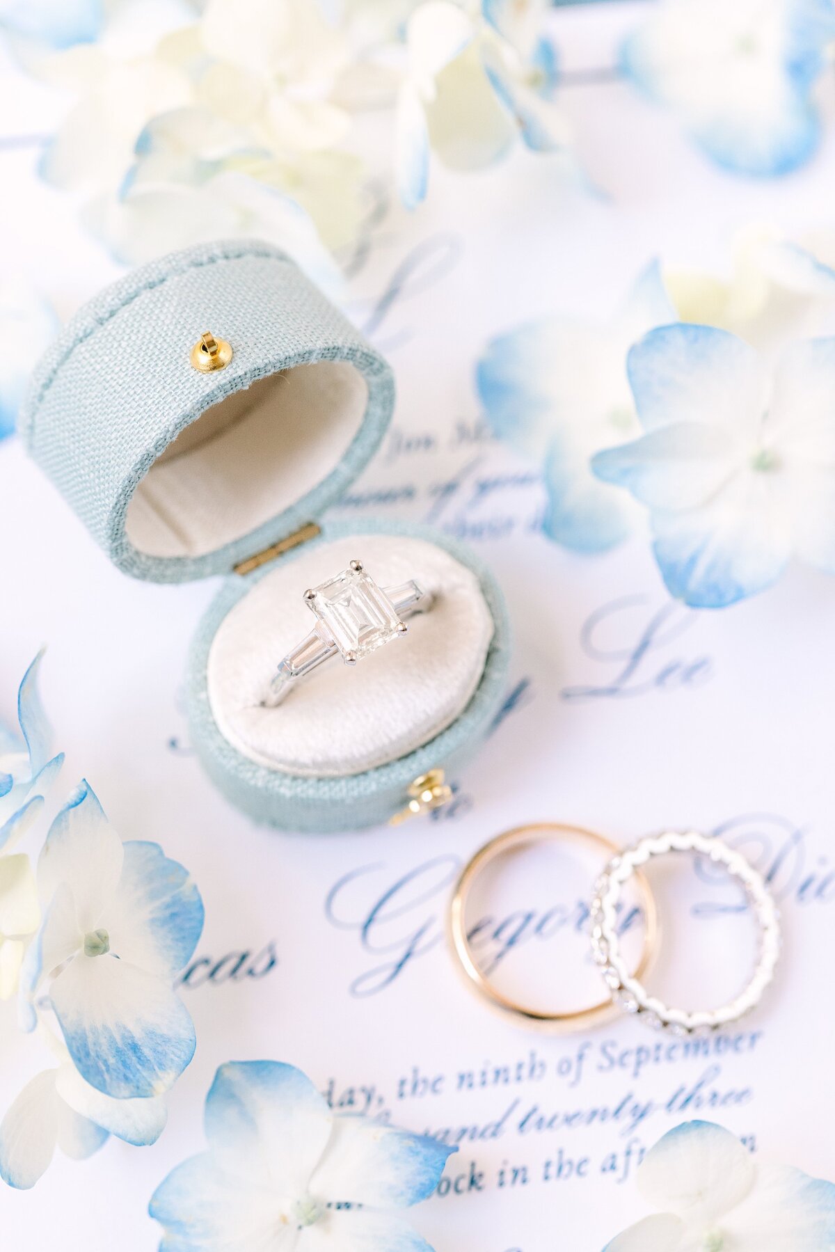 light blue ring box with engagement ring on the invitation suite with hydrangea flowers