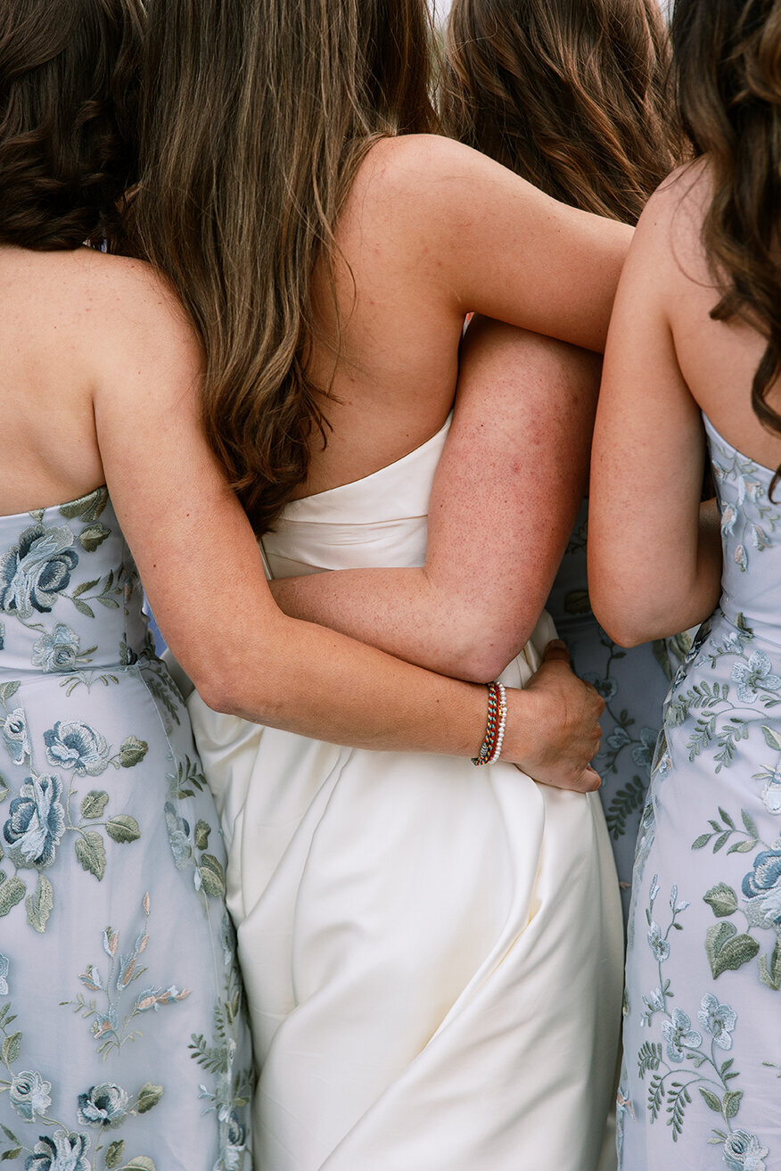 Bride & bridesmaids hugging by Sarah Bradshaw