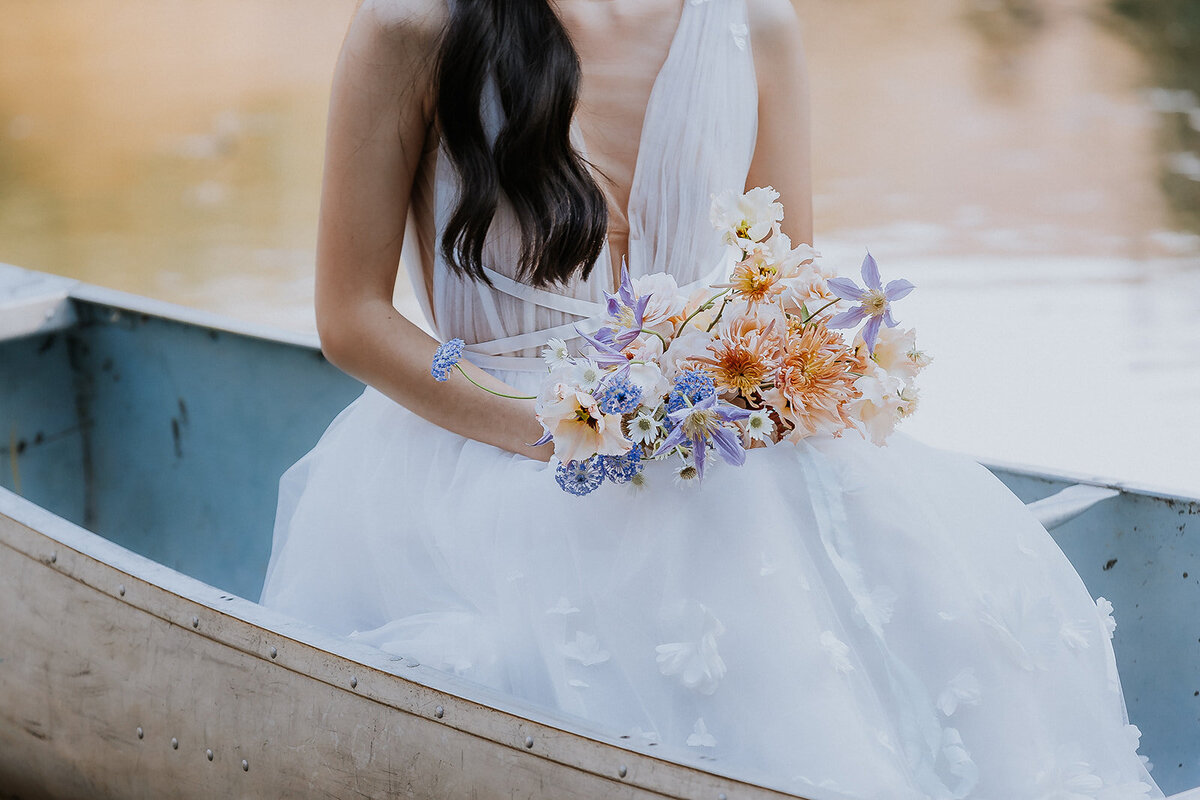 bride and bridal bouquet in a boat at the lake at olympias valley estate, napa