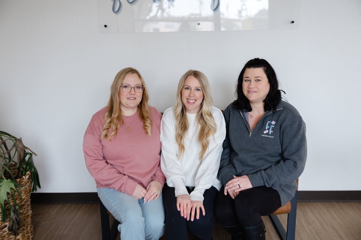 Group of three women smiling while seated together for professional branding photos. Photograph by Yucaipa branding photographer Kaitlyn Dawn Photography.