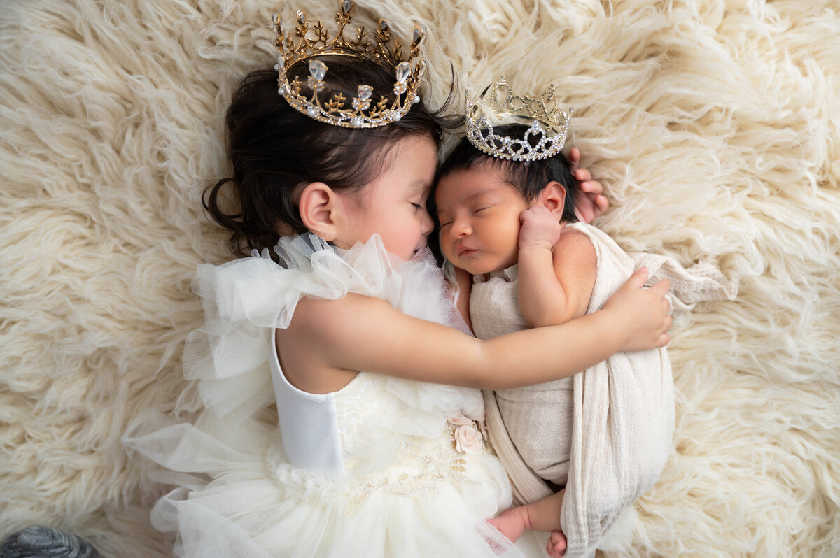 On an off-white flokati, siblings cozy up in formal outfits and matching crowns.
