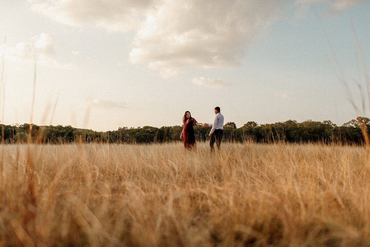 Maternity photo of a couple standing together in a field, photographed by San Antonio family photographer Sara James.