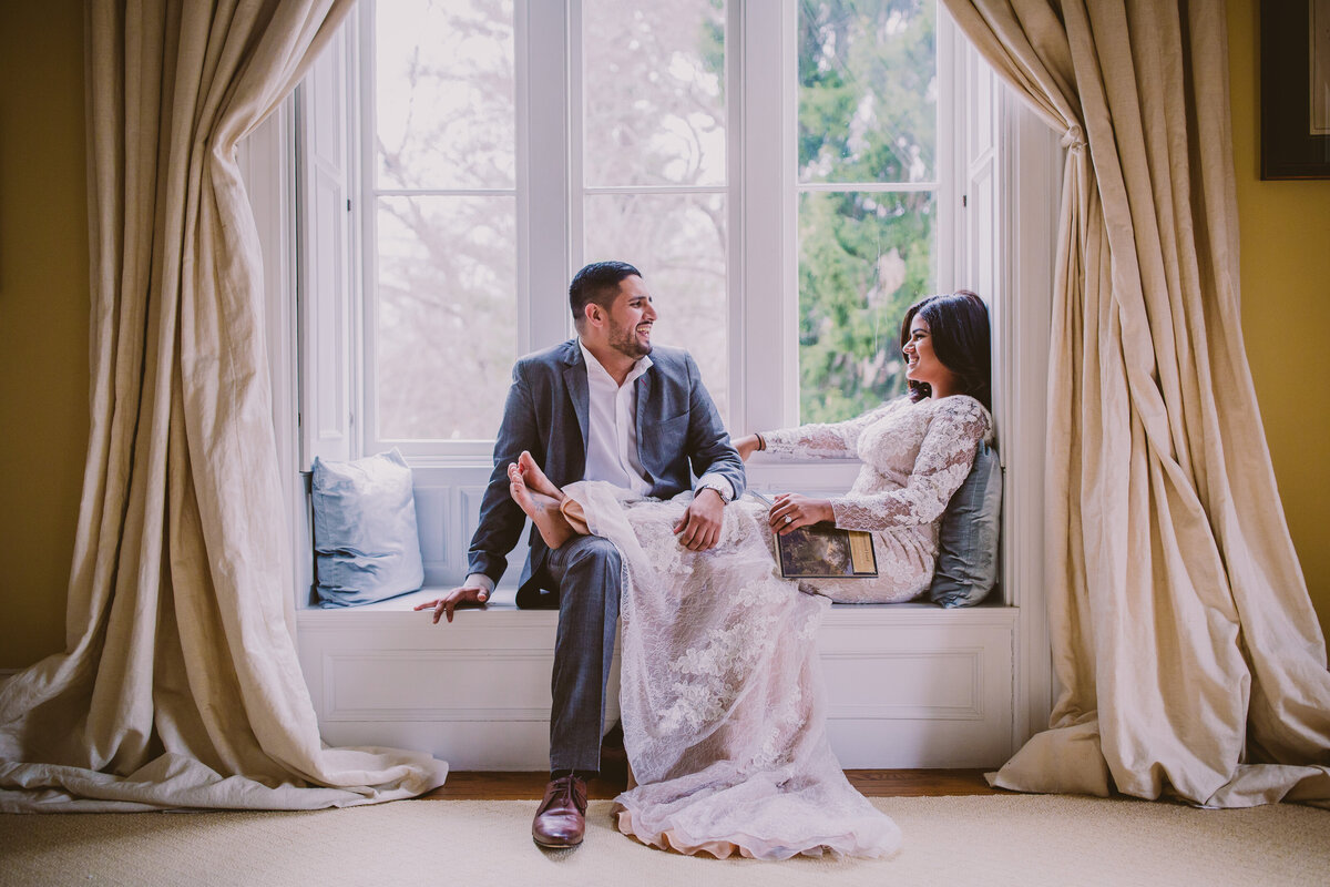 A couple sitting by a nook during their engagement session at the villa nuits bedroom in irvington ny