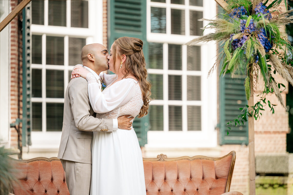 A bride and groom share their first kiss during their garden wedding ceremony