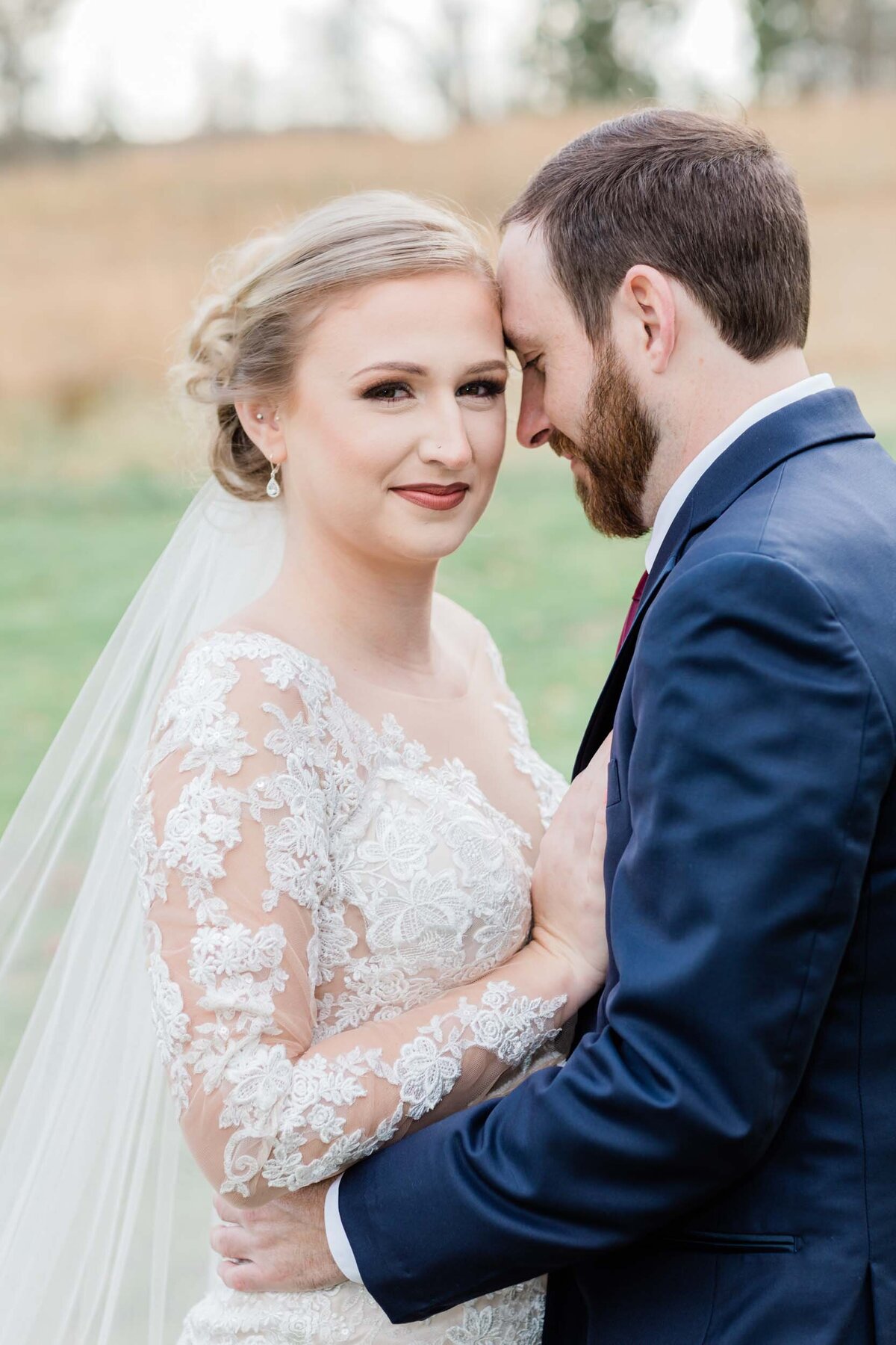 Broom holding his bride close as she looks at the camera.