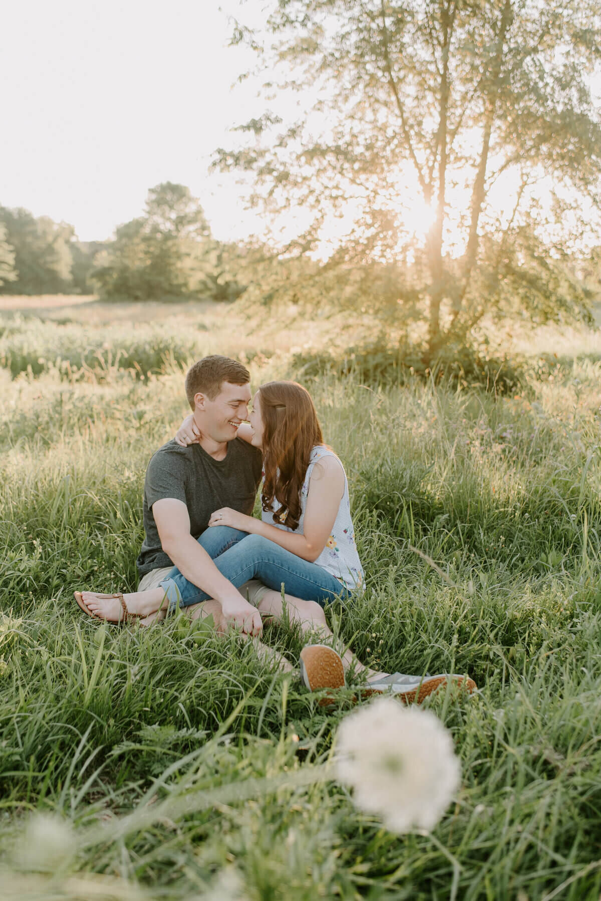 couple sitting in grass field by nashville engagement photographer