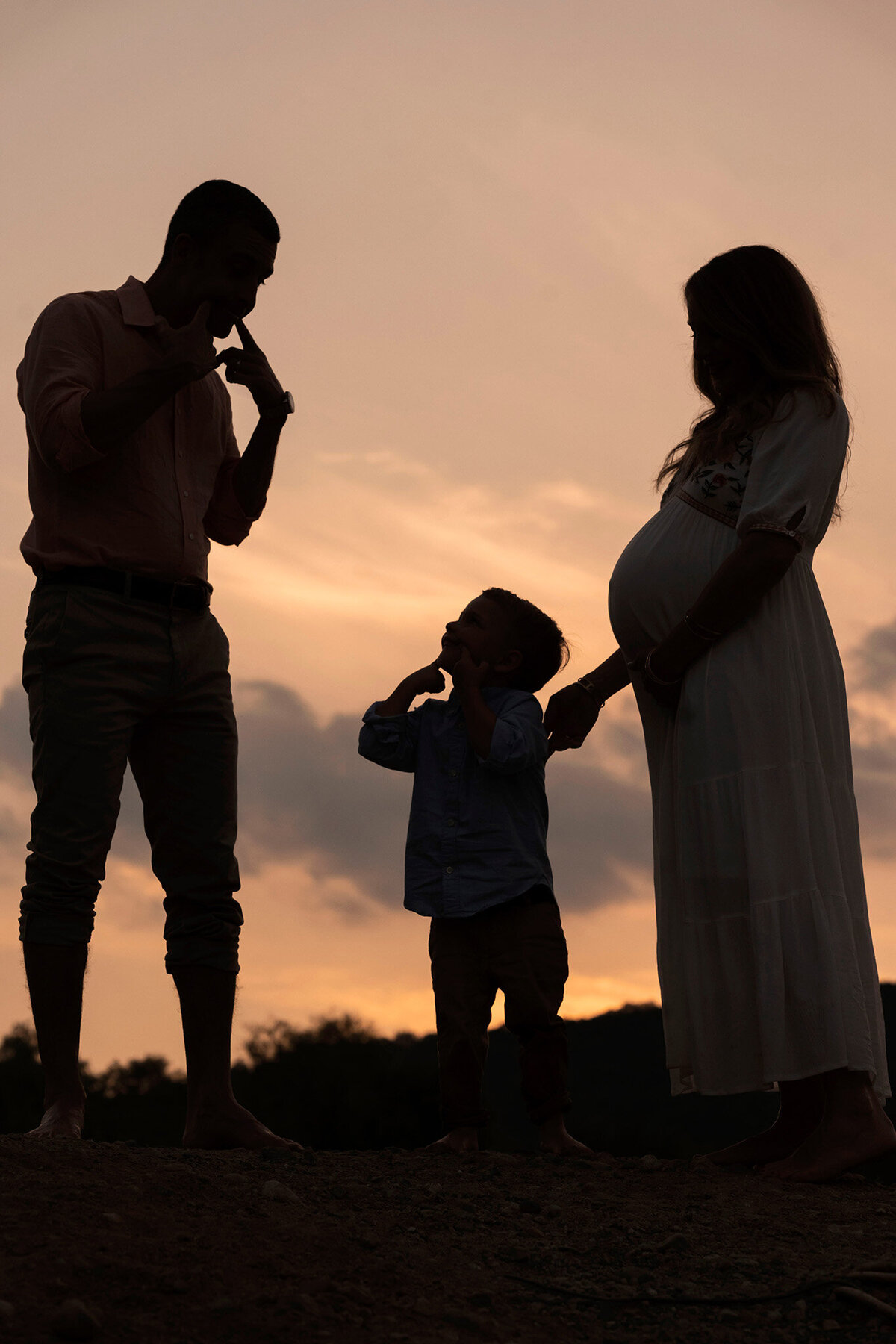 Silhouette photo of expecting family in NJ, highlighting mom's growing belly