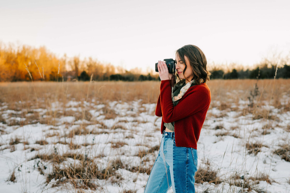 high school senior kneeling holding camera in Branson senior photography session