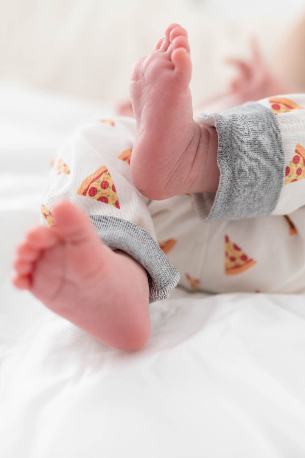 Newborn baby's feet in pizza pajamas.