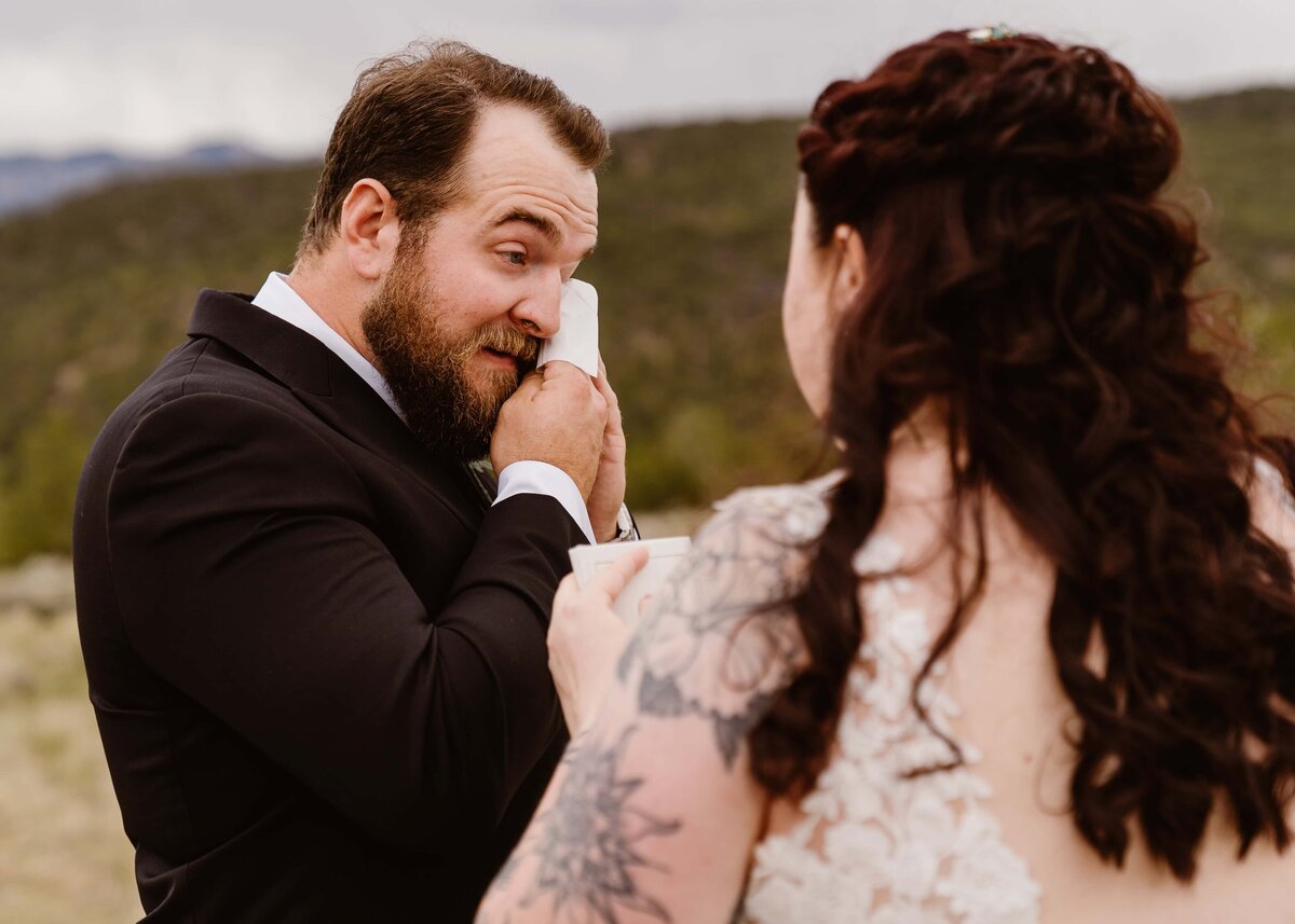 Groom wipes away tears while listening to bride’s vows during their Ridgway State Park wedding ceremony.