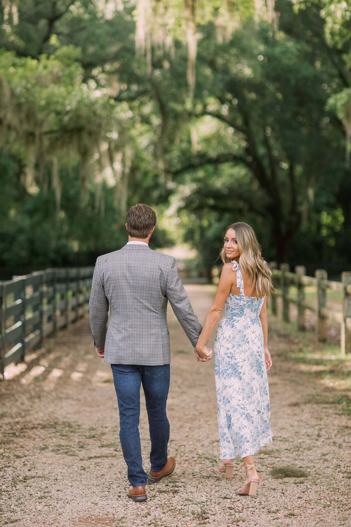 couple walk down path hand in hand as woman looks back over her shoulder