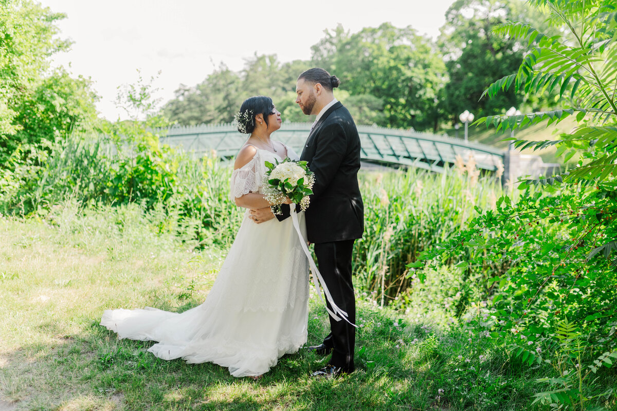 bride and groom posing in park with bouquet and bride behind them during wedding photo session in albany ny