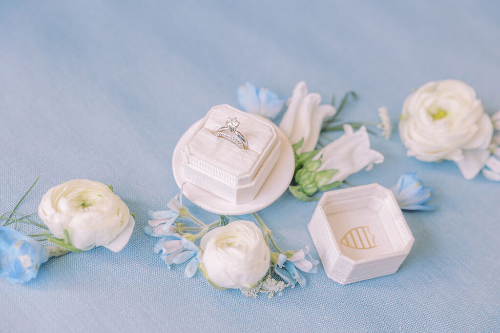 blue flat lay with wedding ring in the mrs box with white and blue florals