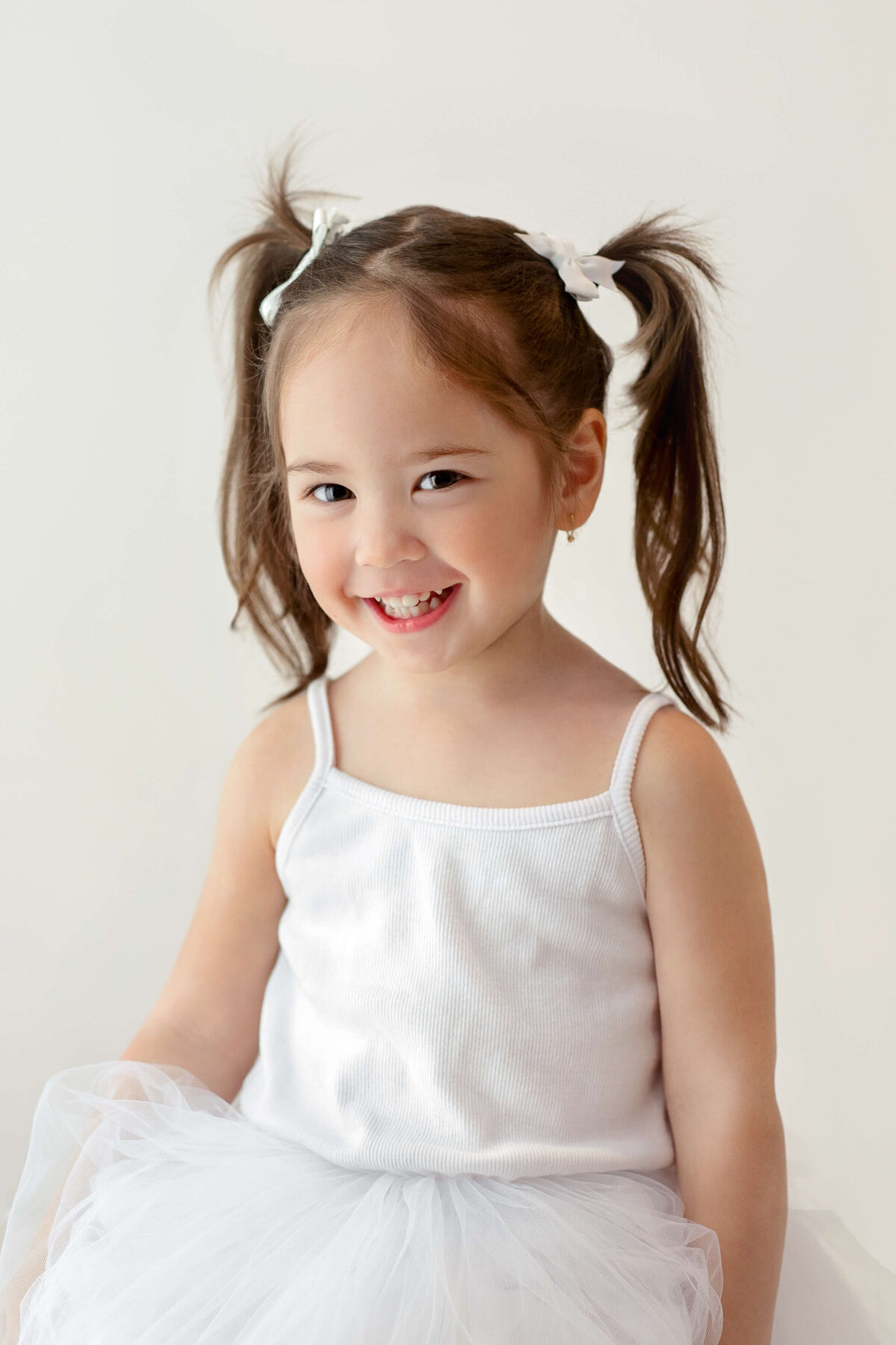4 year old girl with pig-tails in a white dress at a child photography session