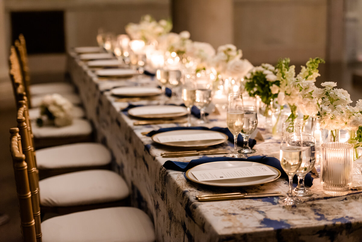 Long head table with patterned linen featuring lush white flowers. Photography Jennifer Nolan