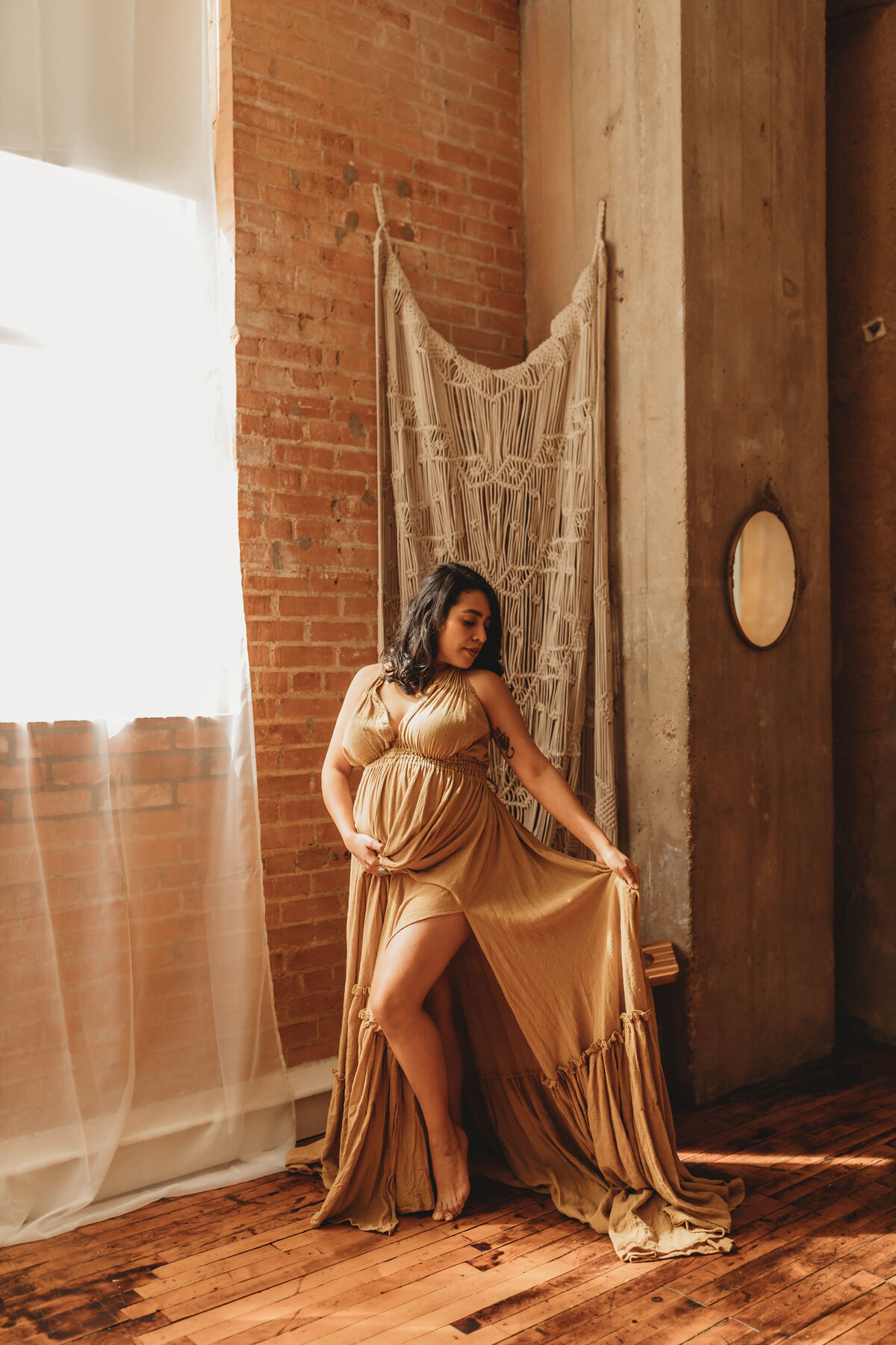 gorgeous expecting mother holding her mustard linen dress in a dallas studio