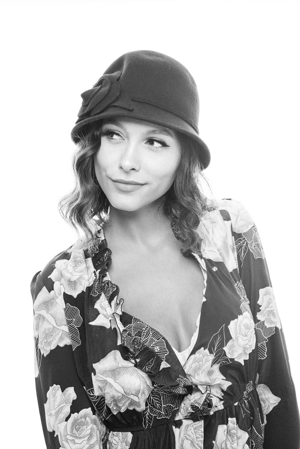 Editorial headshot of a woman in vintage clothing and a bell-style hat on a white backdrop