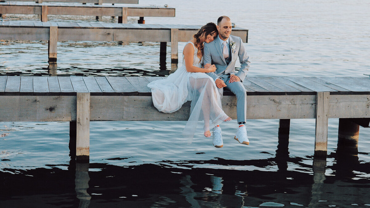 Bride and groom sitting on the dock at the Lakehouse in Canandaigua at sunset
