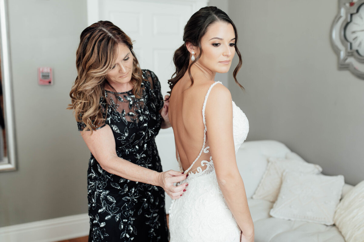 Mom helping bride in her wedding dress. 