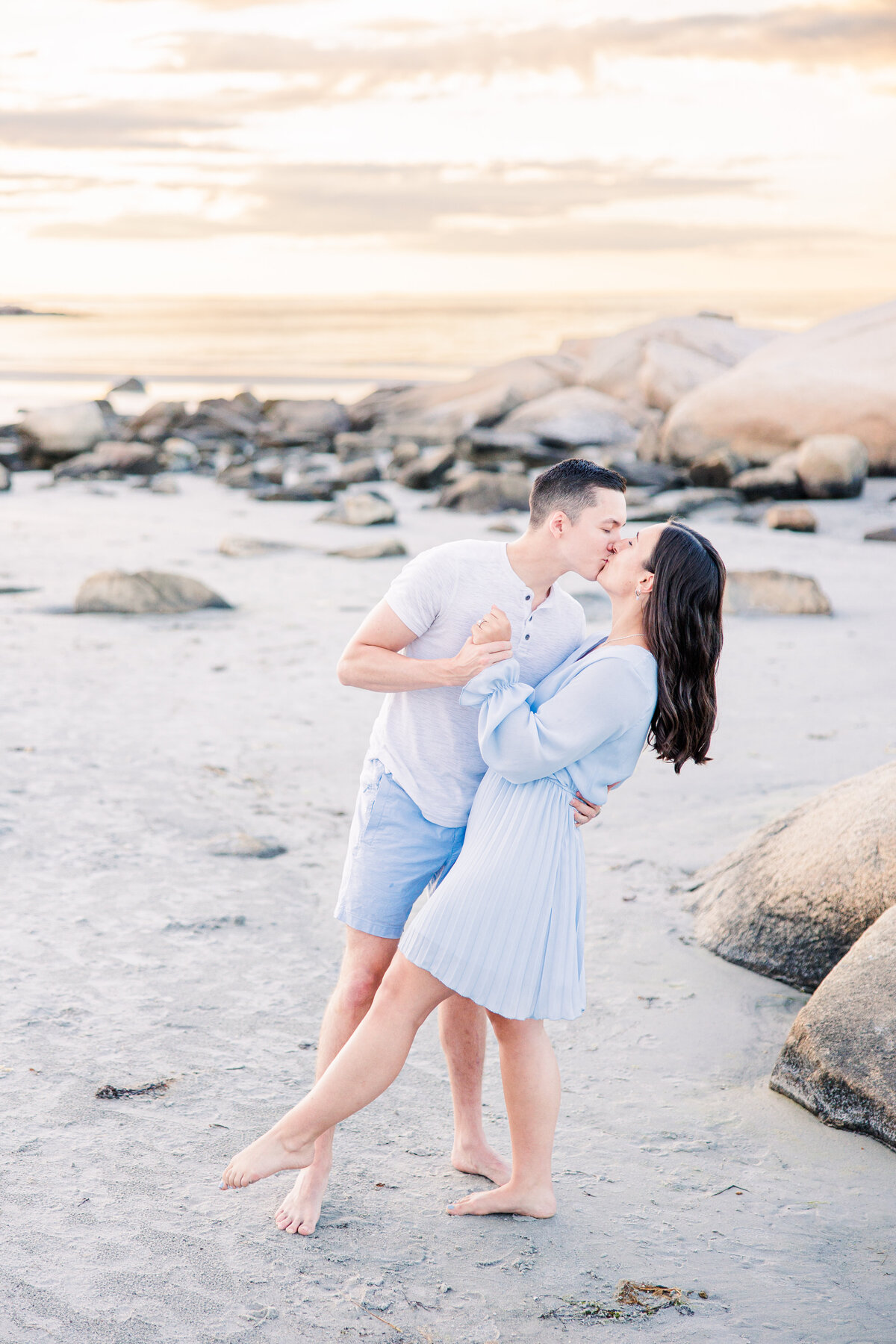 Man dipping and kissing a woman representing romantic MA beach engagement photos
