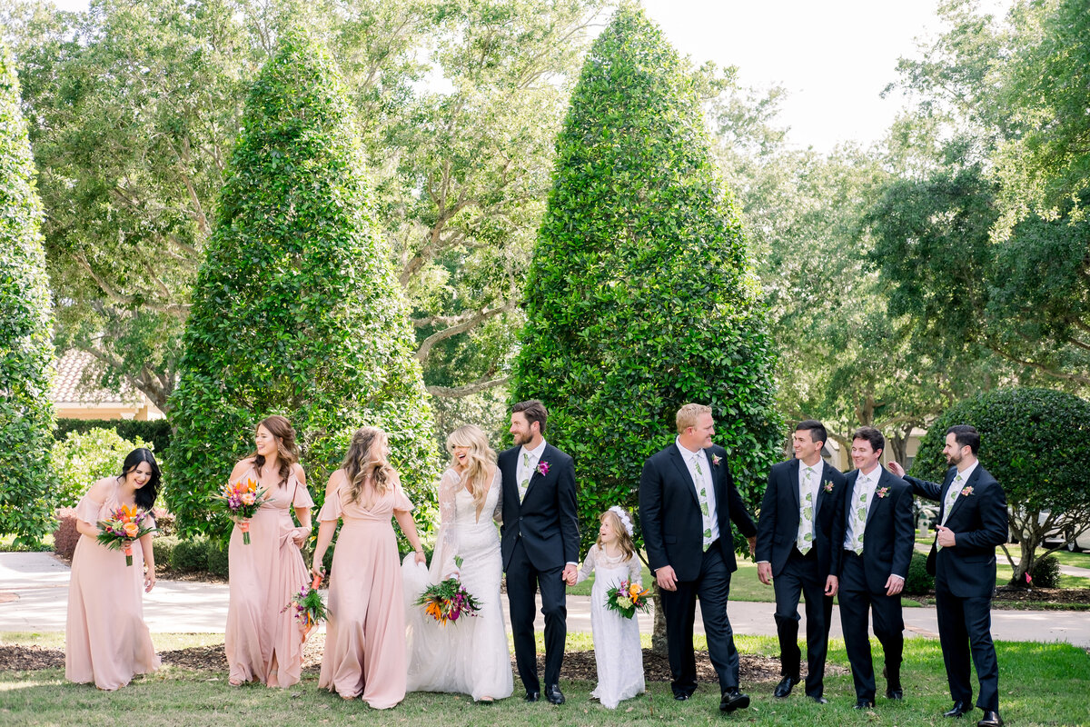 Bridal party lughs as they walk in manicured garden in Private estate in Orlando, Florida