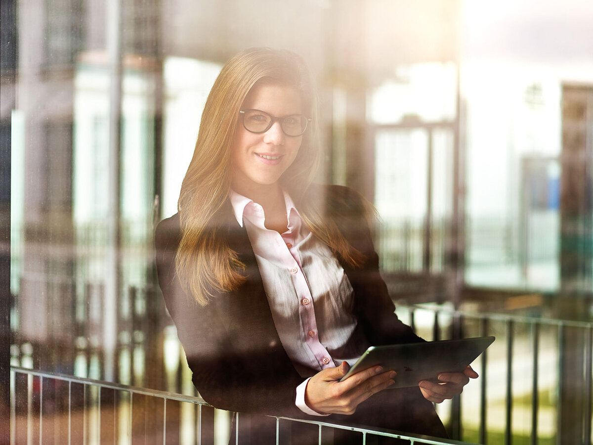 Modernes Businessportrait einer Frau mit Tablet – Atelier Schulte inszeniert digitale Arbeitswelten in urbaner Architektur für innovative Unternehmen.