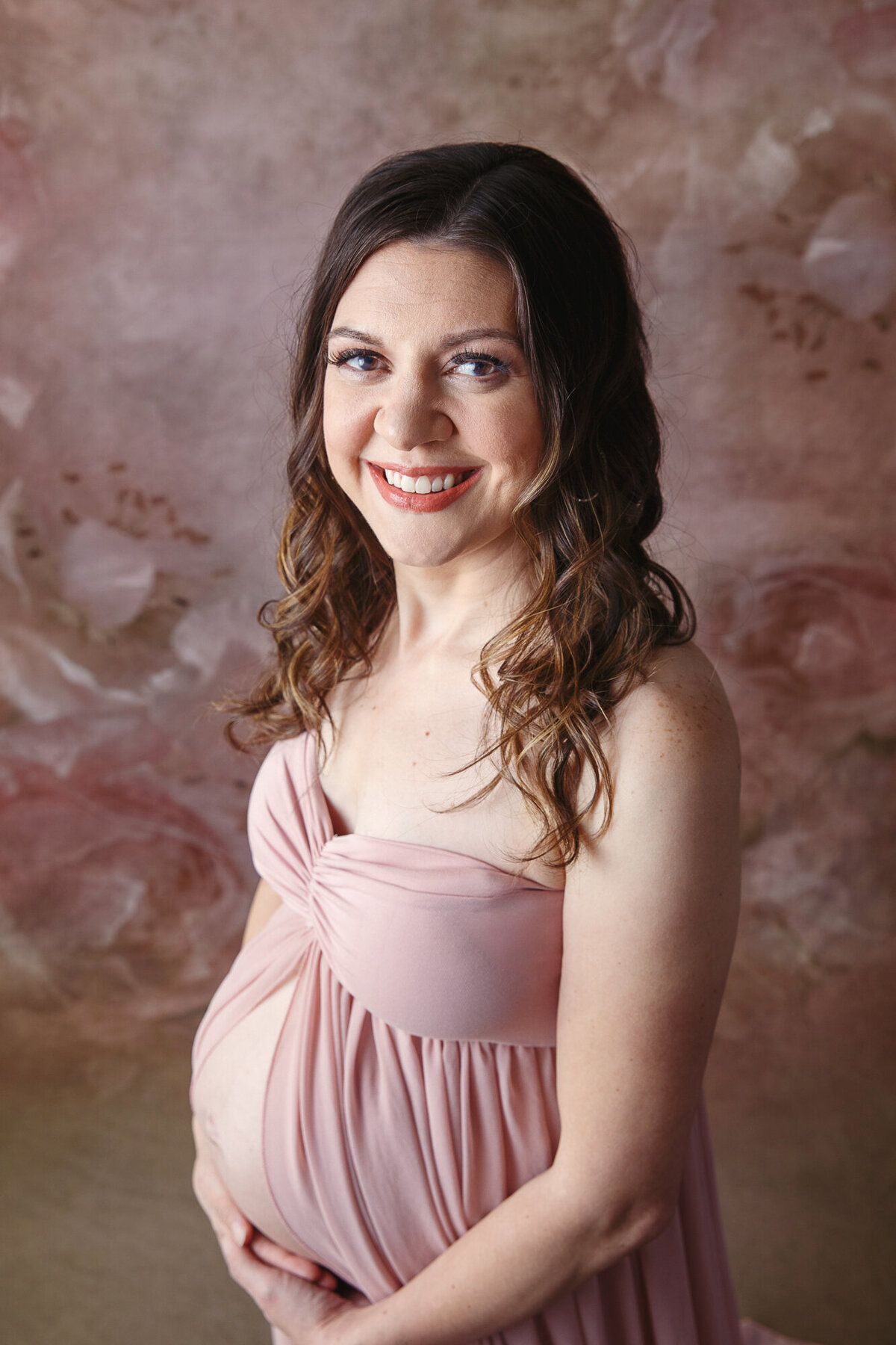 Coseup image of a pregnant woman wearing a pink maternity gown