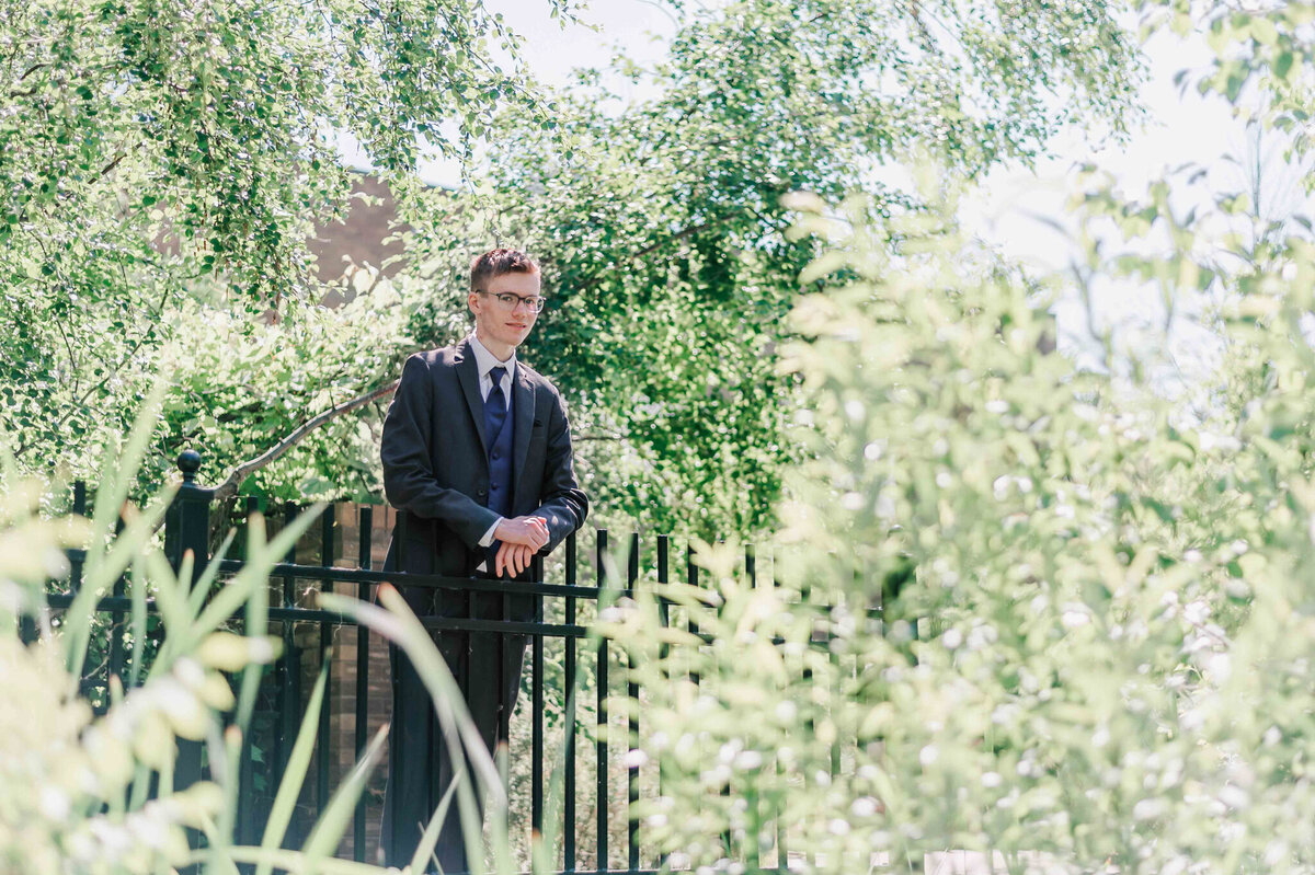 A young man leaning against a black metal fence