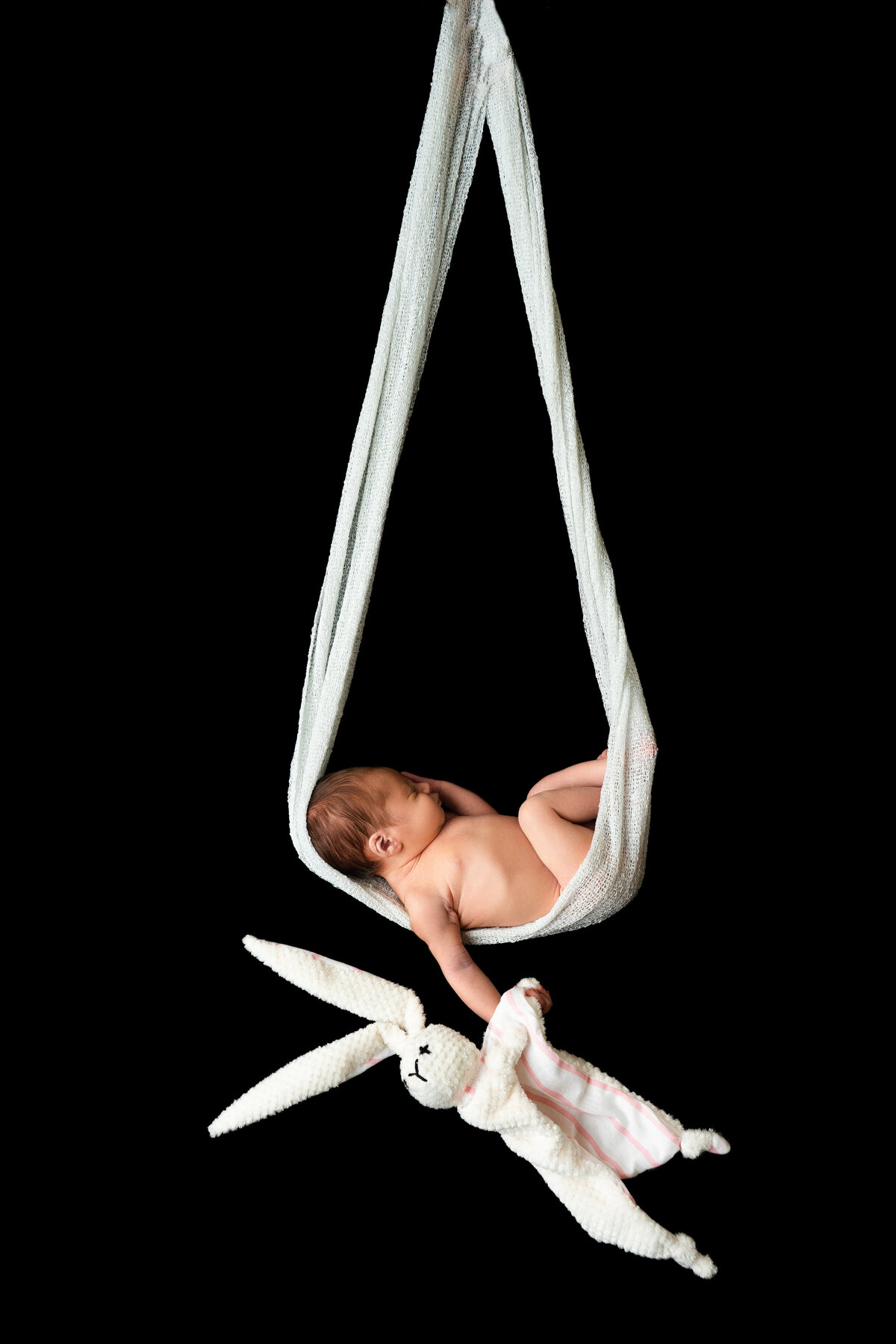 newborn-baby-posing-with-rabbit-on-black-background