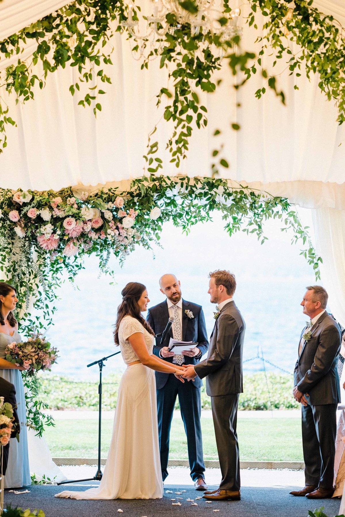 tent wedding ceremony with a romantic pink, white and green floral arch