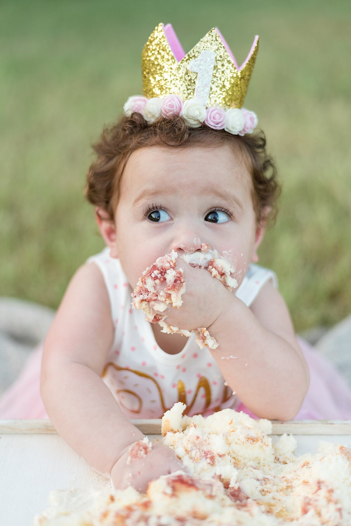 baby looking away eating cake