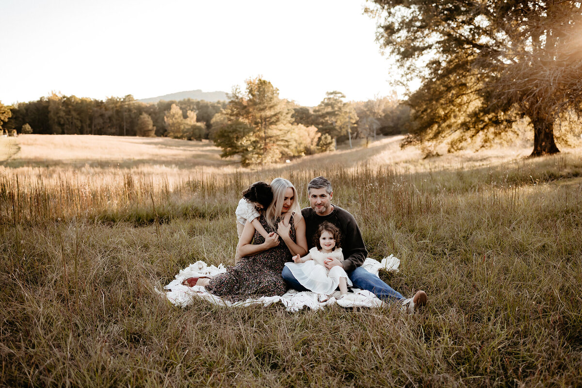 Family photography, family of four standing closely together with hands on each other