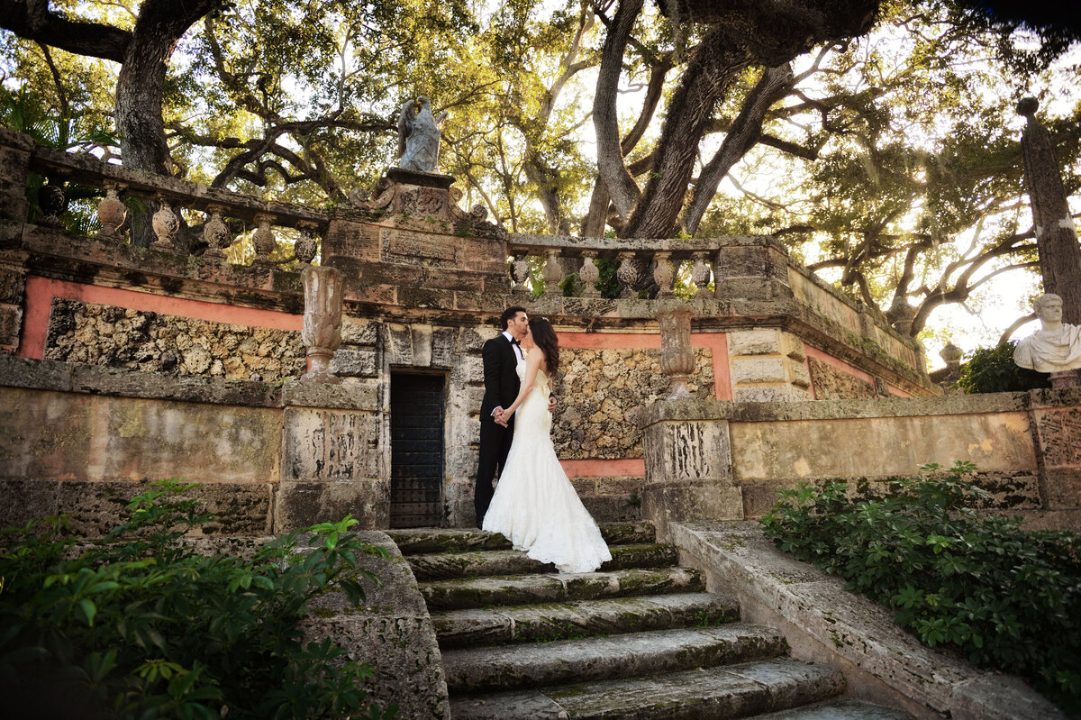 Bride and groom holding hands on the historic stone steps of Vizcaya Gardens in Miami, Florida, captured by Rodrigo Varela Photography.