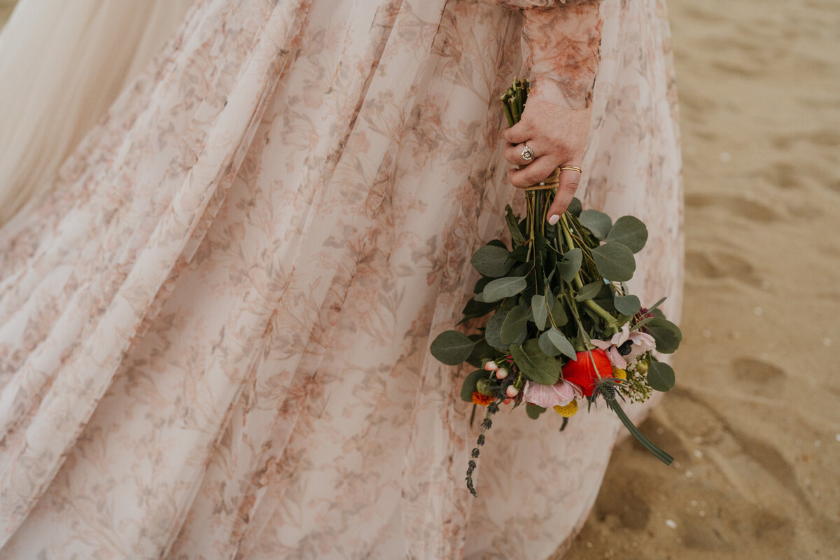 A close up of someone in a wedding dress holding a bouquet of flowers 