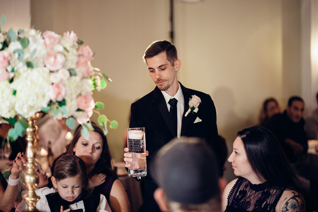 Wedding Photograph Of Groom In Black Suit Raising a Glass With Visitors Around Los Angeles