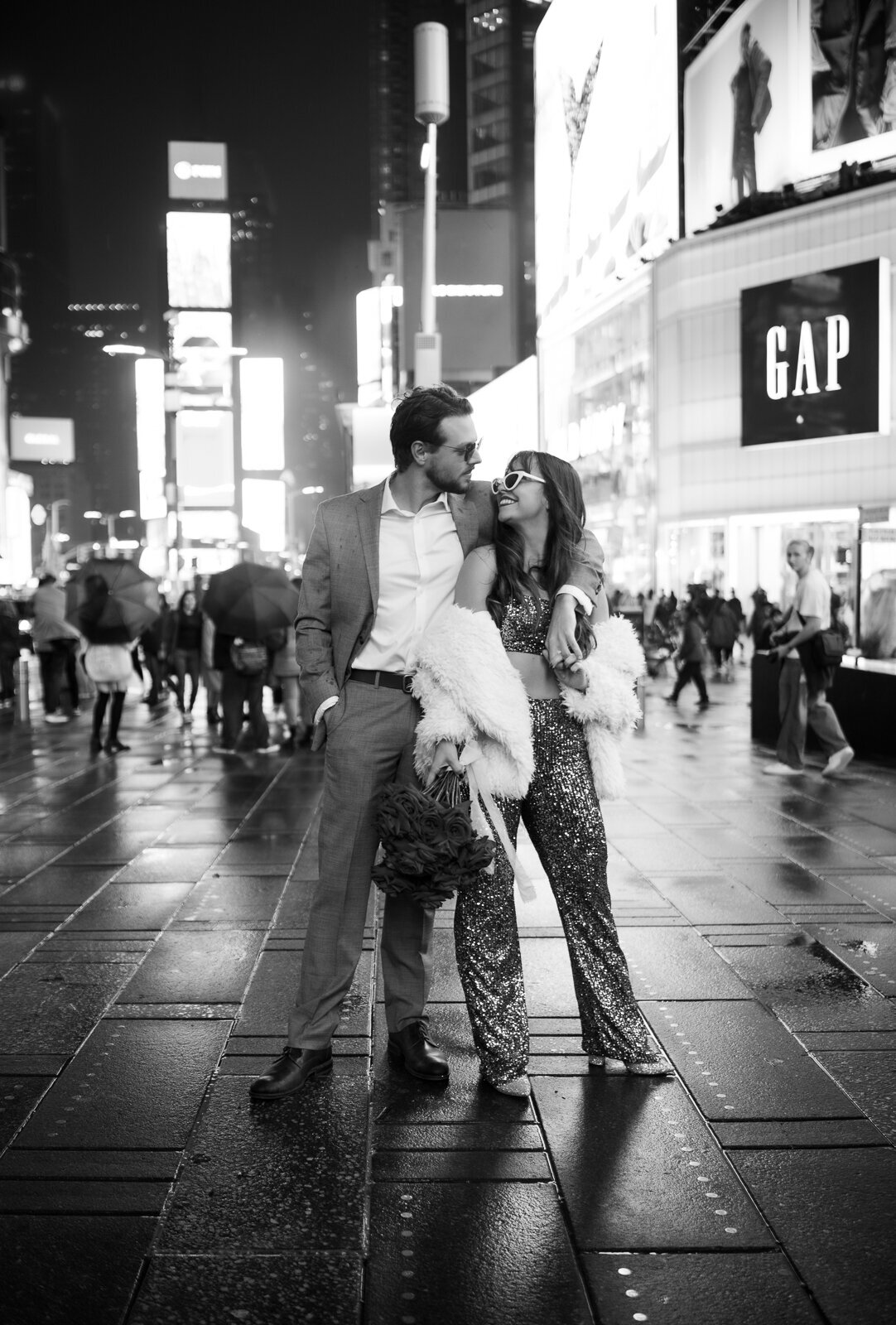 A couple wearing shades smiling at each other in Times Square, New York.