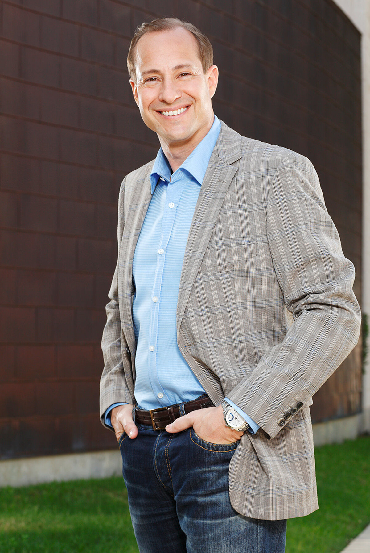 A man smiling with both hands in his pockets