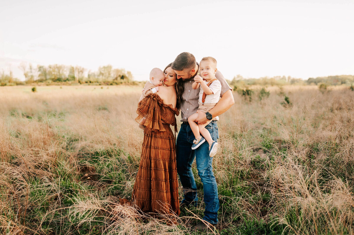 family snuggling and holding flowers in field enjoying Branson family photography