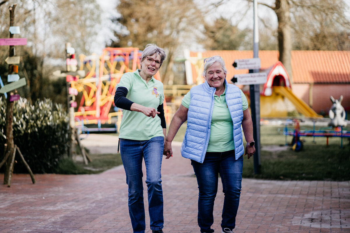 Collega's die samen lachen en ontspannen in speelpark Sprookjeshof, omringd door speeltoestellen en een vrolijke sfeer. 