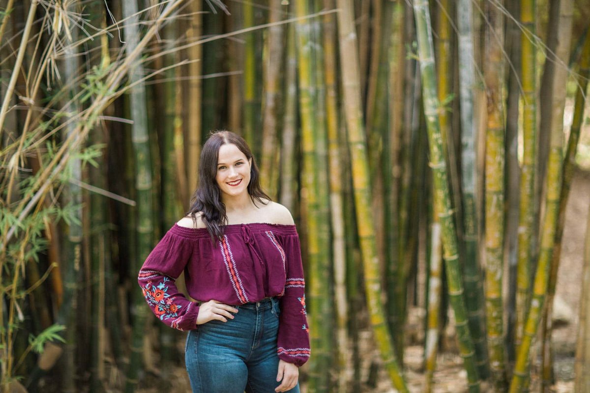 Young lady poses amongst a bamboo forest for her college senior photo shoot