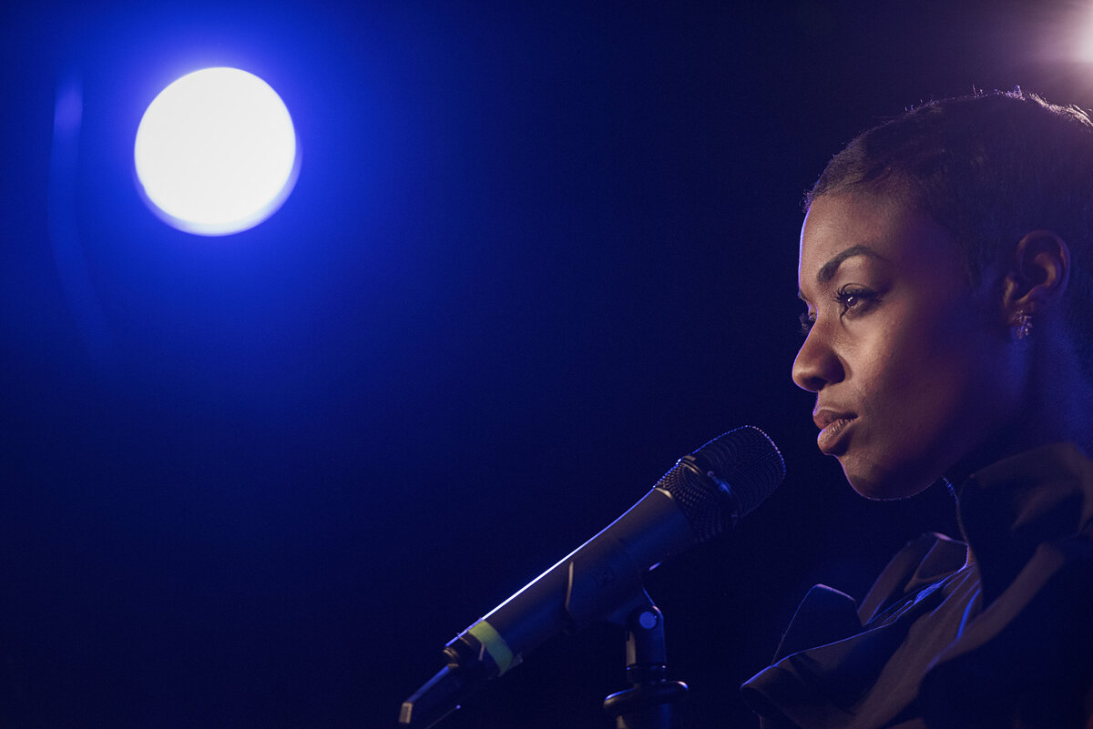A person standing at a microphone with a spotlight on them