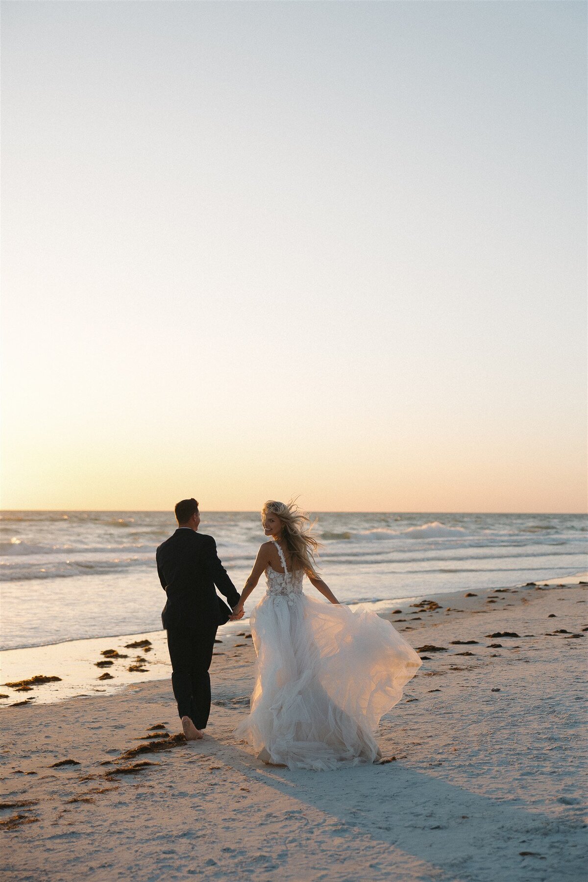 Bride and groom walk off into the waves barefoot in stunning Florida elopement ceremony
