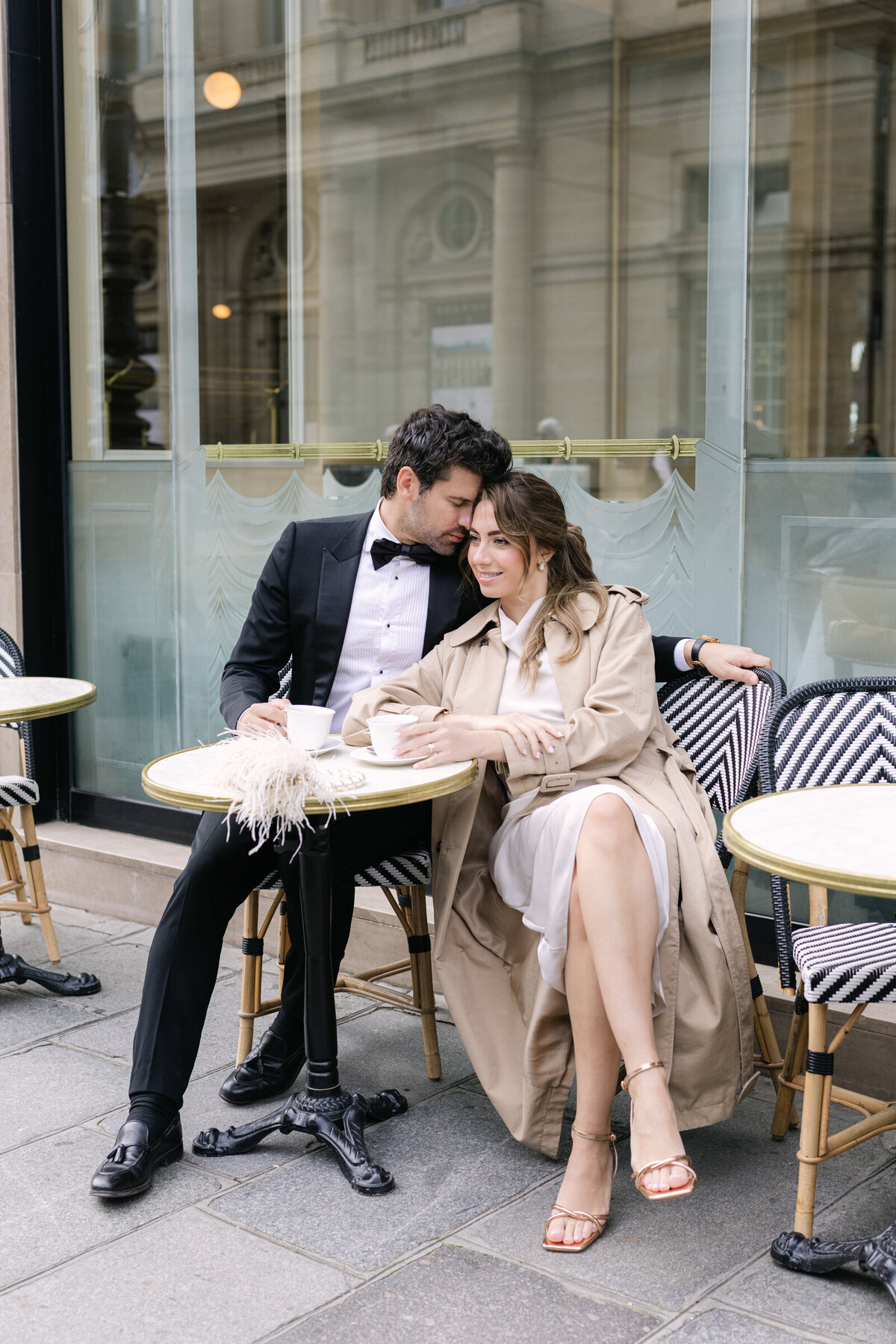 Couple seated at a charming Parisian cafe, sharing a quiet moment during their engagement session.