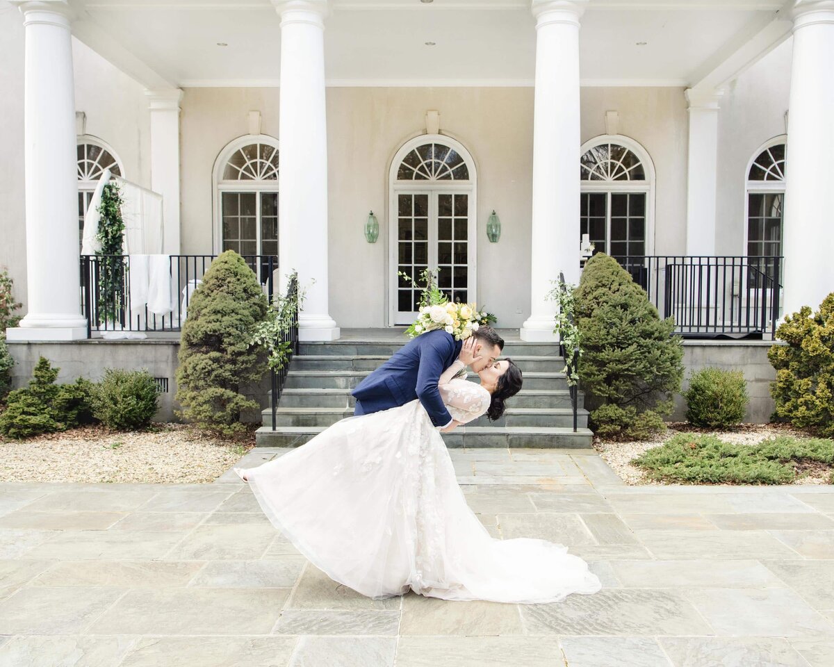 Groom and bride kiss in front of venue