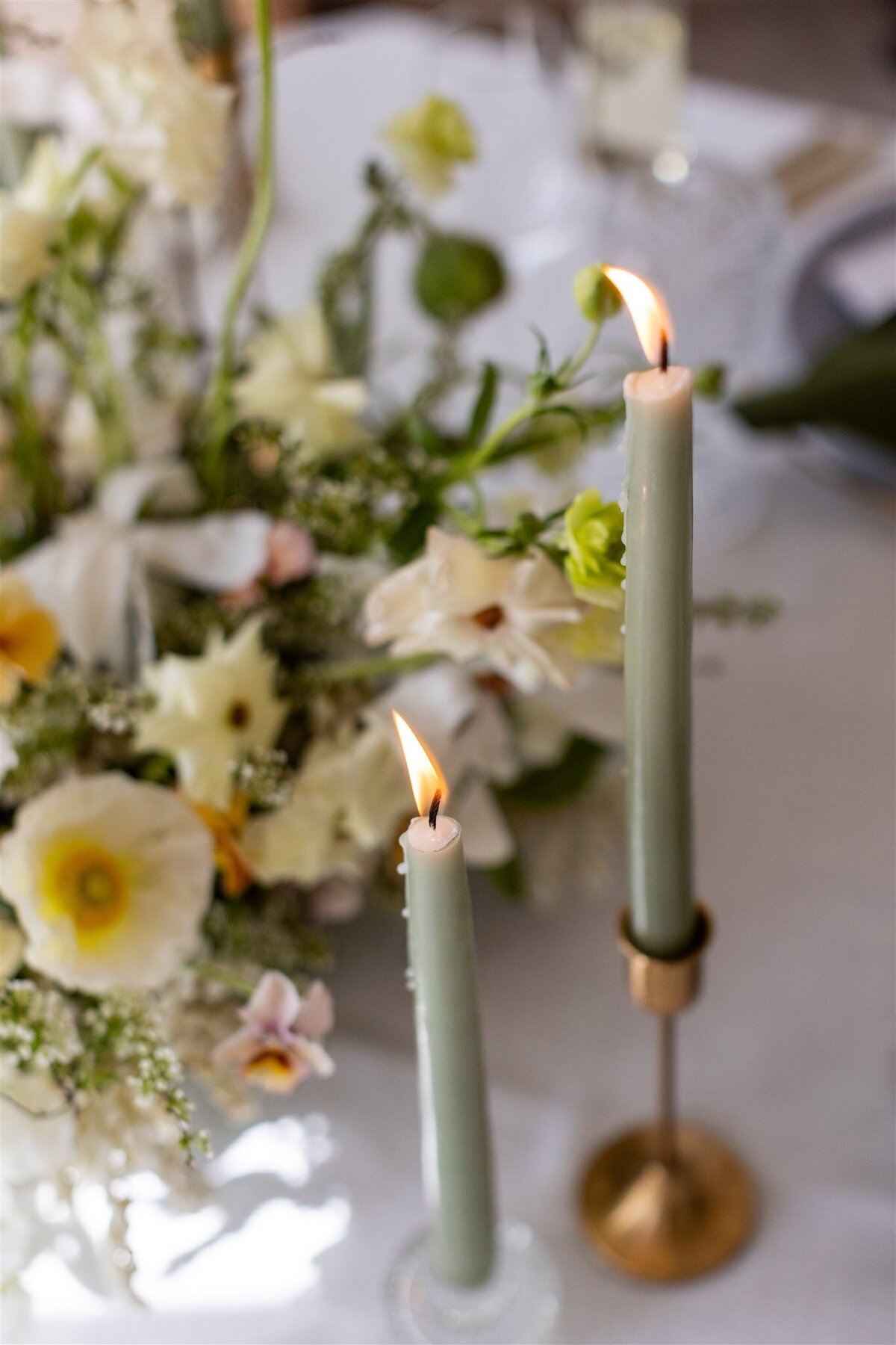 Wedding table design with whimsical floral design and green taper candles lit.