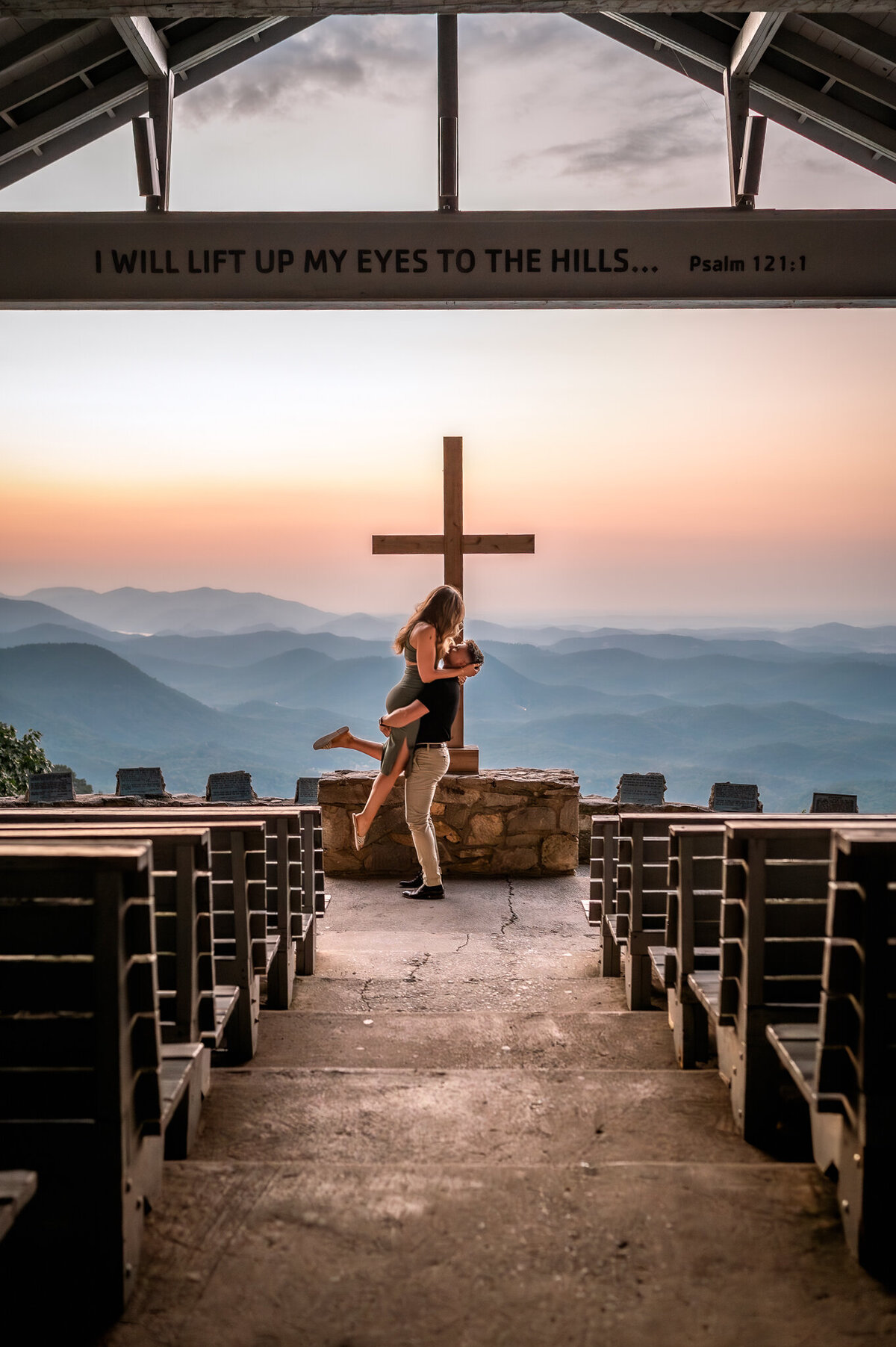 A religious couple who just got engaged in pretty place south carolina in a chapel overlooking the mountains with a cross